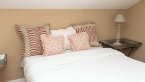 A neatly made bed with white and patterned pillows, a bedside table with a lamp, and a small mirror on the wall. - Tranquil & Family-friendly 3BD Home, Clapham! (London)