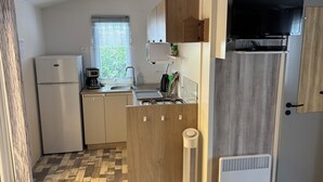 Kompakti keittiö, jossa on jääkaappi, kahvinkeitin, pesuallas ja televisio.