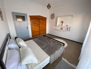 A bedroom with a bed, a wardrobe, a mirror, and a wall-mounted shelf. - A very quiet apartment in the heart of downtown. (Alger Centre)