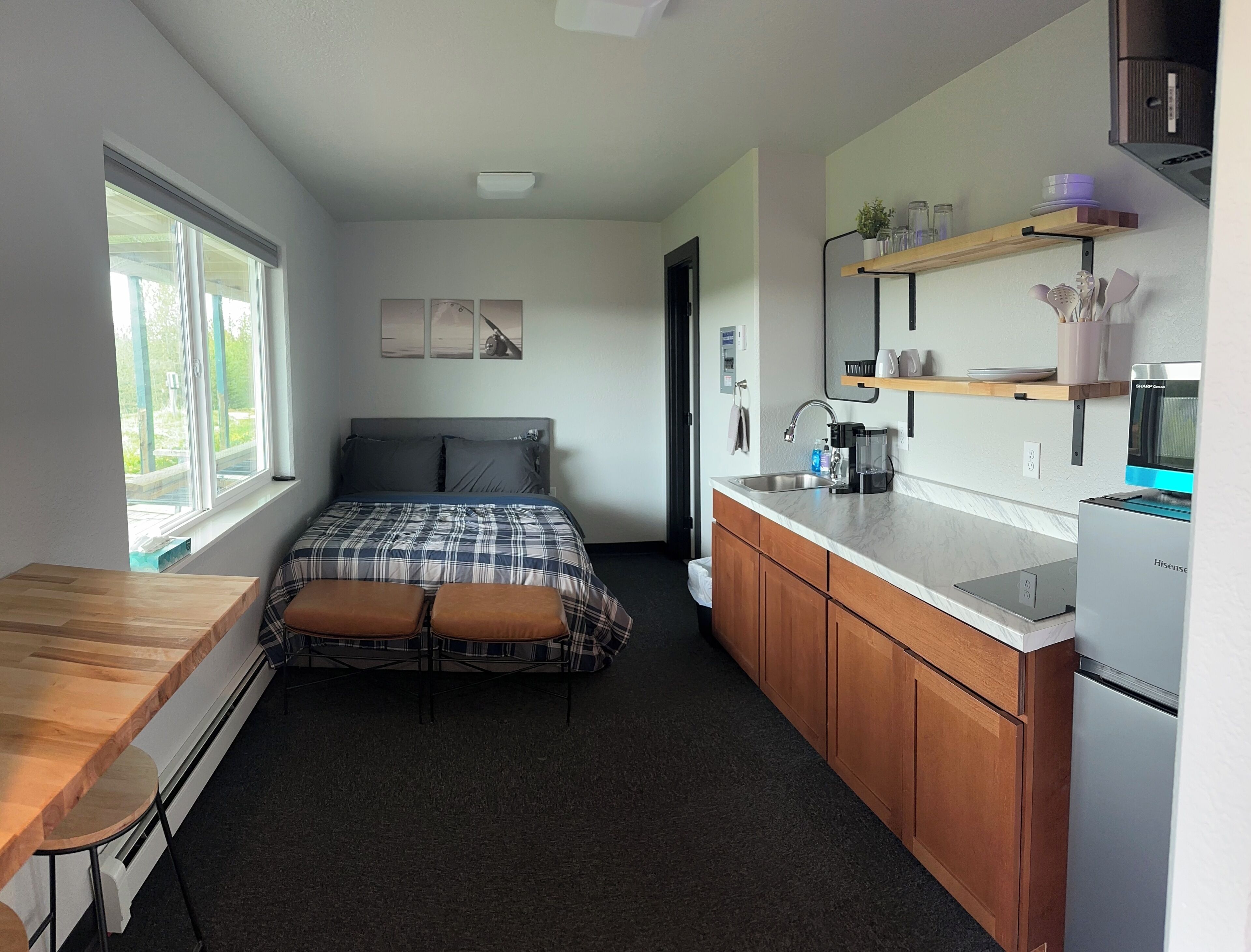 Quarto compacto com uma cama, uma cozinha compacta e um espaço de jantar.