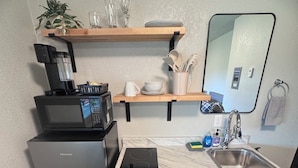 Una cucina compatta con forno a microonde, piano cottura a induzione Hisense, lavandino e un piccolo ripiano.