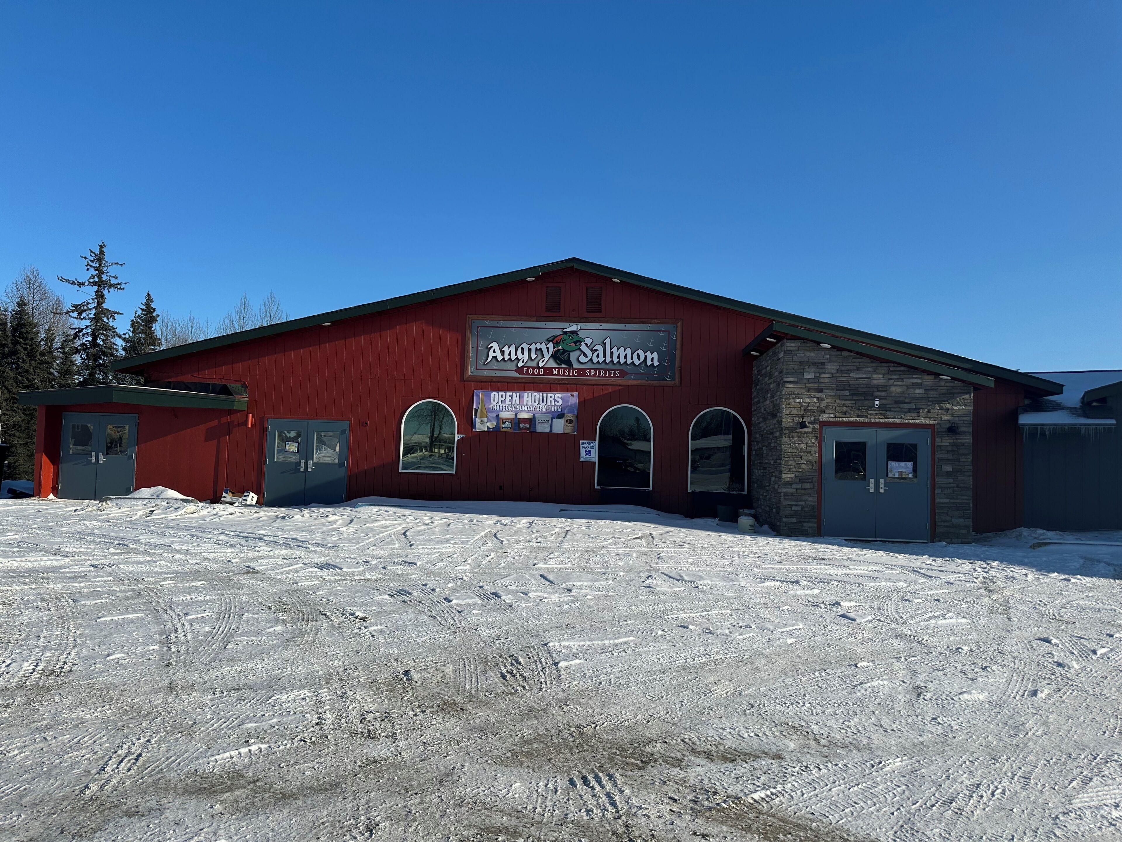 A red building with a sign for 'Angry Salmon Food Music Spirits' and a snow-covered ground.