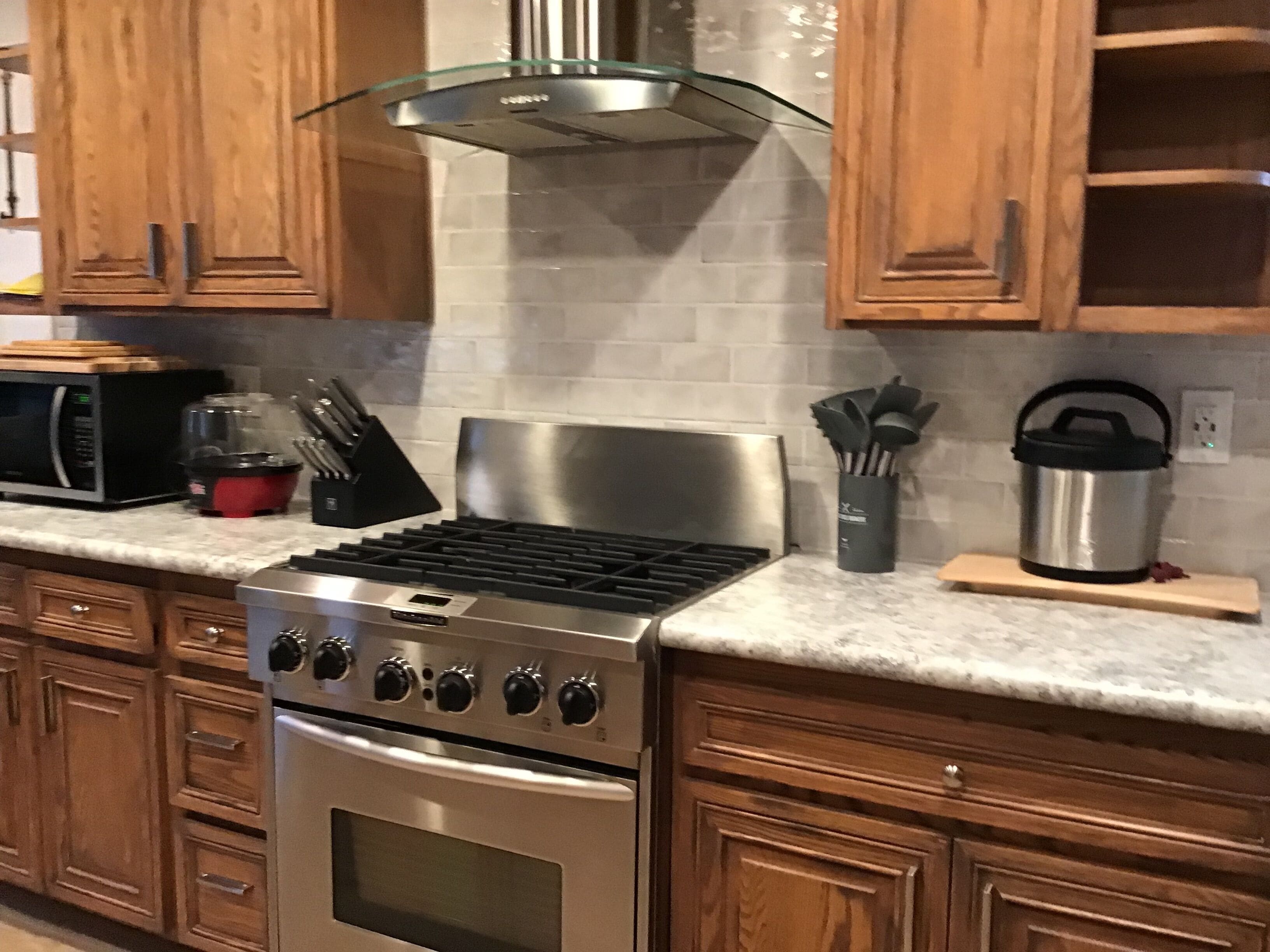 Uma cozinha com armários de madeira, um fogão de aço inoxidável e um micro-ondas.