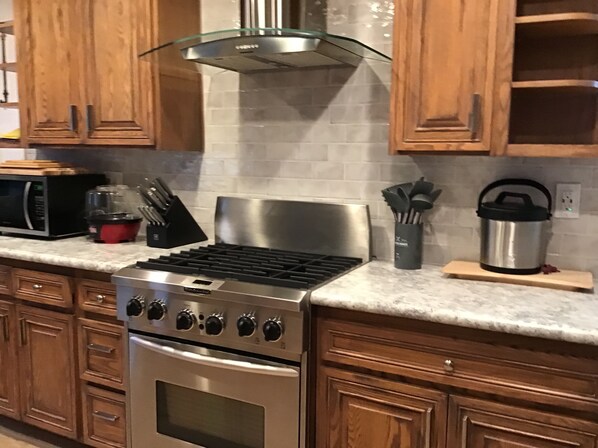 A kitchen with wooden cabinets, a stainless steel stove, and a microwave.