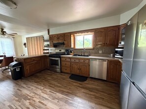A kitchen with wooden cabinets, stainless steel appliances, a window, and a wooden floor. - Spacious Wisconsin Northwoods Escape -Private Fire Pit and Close Water Access (Porterfield)