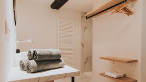 A bathroom with a marble floor, a towel rack with towels, a wooden shelf, and a towel dispenser. - Josephine: romantic room in a historic mansion, heart of Antwerp (Antwerp)
