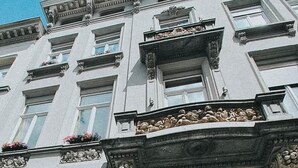 A multi-story building with ornate architectural details, including decorative moldings and a balcony with flower boxes. - Josephine: romantic room in a historic mansion, heart of Antwerp (Antwerp)