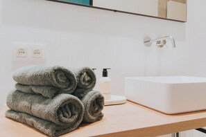 A bathroom with a white sink, a towel dispenser, and a mirror.