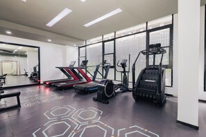 Ein Fitnessraum mit Laufbändern, Crosstrainern und Rudergeräten.