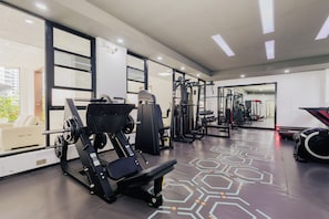 Un gimnasio con equipo de ejercicio, una cinta de correr y un espejo grande.