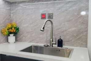 Een moderne keuken met een roestvrijstalen spoelbak, een vaas met bloemen en een marmeren achterwand.