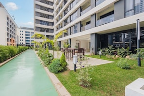 Een modern gebouw met meerdere verdiepingen, een binnentuin met groen en een zwembad.