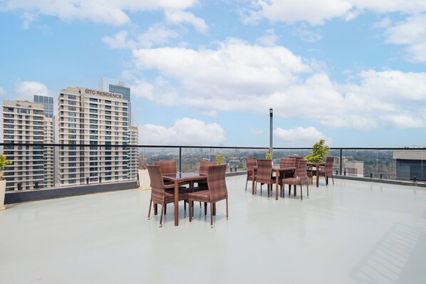 Terraza en la azotea con mobiliario de mimbre y vistas a la ciudad.