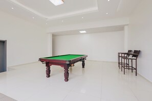 Una habitación amplia con mesa de billar, una silla y una puerta.