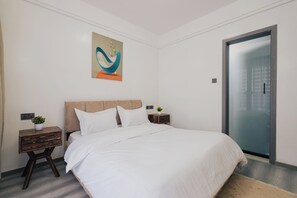 Ein Schlafzimmer mit einem Bett, einem Nachttisch, einem Wandbild und einer Tür.