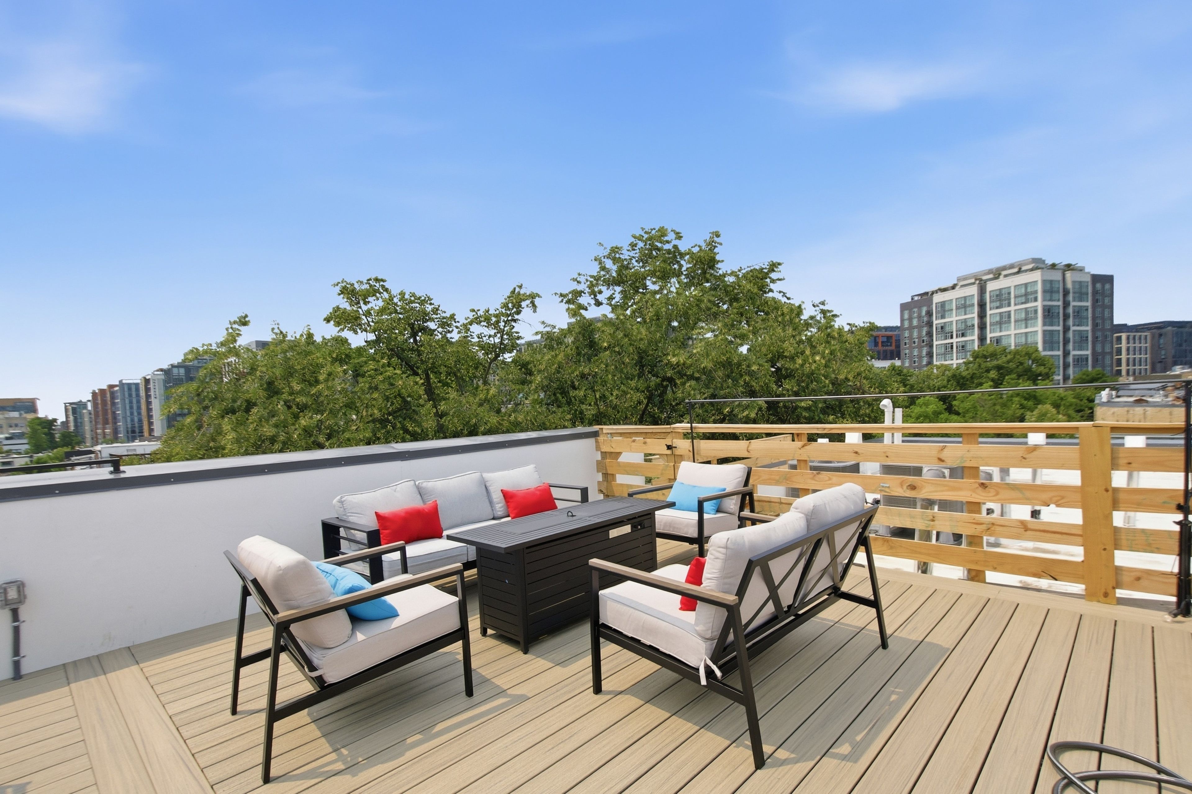 A rooftop terrace with outdoor furniture, a wooden deck, and a cityscape view.