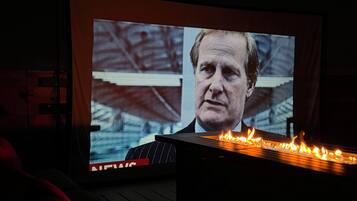 A large screen displaying a news broadcast with a visible 'NEWS' label.