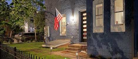 A building with a dark facade, a flag, and a well-lit entrance.