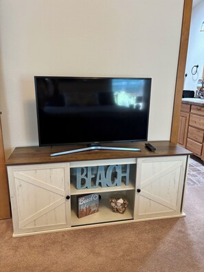 Un televisor de pantalla plana sobre un mueble de madera, con un letrero que dice 'BEACH' y otro que dice 'Beach Life' debajo.