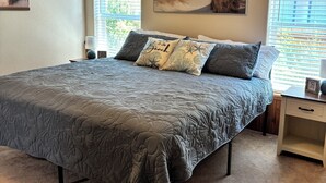 Ein Schlafzimmer mit einem großen Bett, zwei Nachttischen, einer Kommode und zwei Bildern an der Wand.