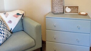 Ein Zimmer mit einem hellblauen Sofa, einer grauen Kommode mit Schubladen, einem gerahmten Bild an der Wand und einem dekorativen Gegenstand auf der Kommode.