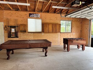 Un intérieur en bois comprenant une table de billard, un baby-foot et des armoires.