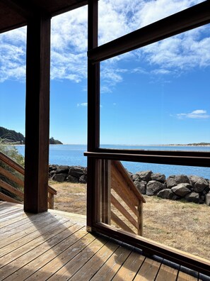 Una terraza de madera con vistas a un cuerpo de agua tranquilo y un cielo despejado.