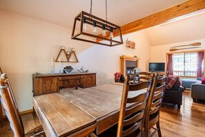 A dining area with a wooden table and chairs, a wooden cabinet, a fireplace, and a television in a cozy room. - Spacious 4-bedroom house near the Deschutes River (Bend)