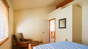 Un dormitorio con cama, una silla, una puerta y una ventana con persianas.