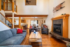 A spacious living area with a fireplace, a sofa, a coffee table, and a dining area with chairs. - Spacious 4-bedroom house near the Deschutes River (Bend)