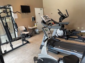 A gym with cardio equipment, a mirror, a television, and a small table with a tissue dispenser. - Spacious 4-bedroom house near the Deschutes River (Bend)