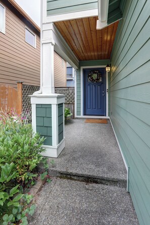 A house with a blue door, a wooden porch, and a small garden area. - Peaceful Bothell Home 3B2.5B for Extended Stay (Bothell)