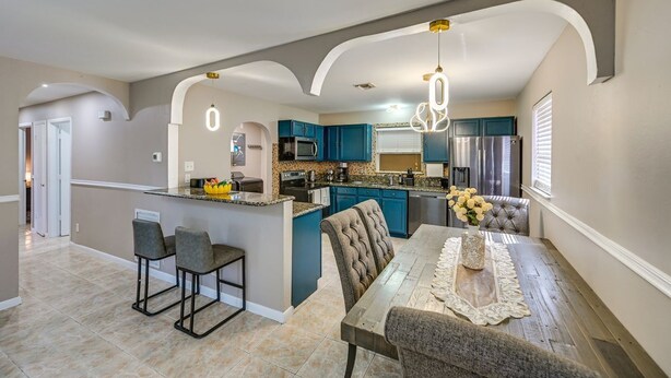 A spacious kitchen with blue cabinets, a central island, and a dining area with a table and chairs. - 3-bedroom house in tranquil Naples with cool AC comfort (Naples)