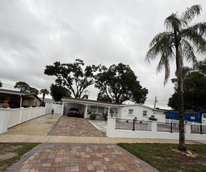 Ein Wohngebiet mit einer gepflasterten Auffahrt, die zu einem Haus führt, umgeben von Bäumen und einem weißen Zaun.