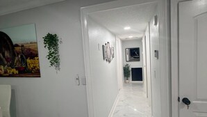 Käytävä, jossa on marmorilattia, valkoiset seinät ja ovi oikealla puolella.