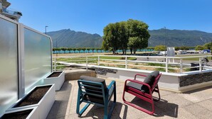 Eine Terrasse mit Sitzgelegenheiten im Freien, Blick auf einen See und Berge in der Ferne.