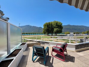 A terrace with outdoor seating, a view of a lake, and mountains in the distance. - Esplanade du Lac, 3 personnes T2 terrace parking (Aix-les-Bains)