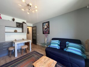 A modern living space with a dining area, a sofa, and a coffee table. - Esplanade du Lac, 3 personnes T2 terrace parking (Aix-les-Bains)