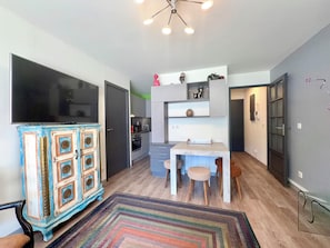 A compact kitchen with a dining area, a television, and a cabinet with decorative elements. - Esplanade du Lac, 3 personnes T2 terrace parking (Aix-les-Bains)