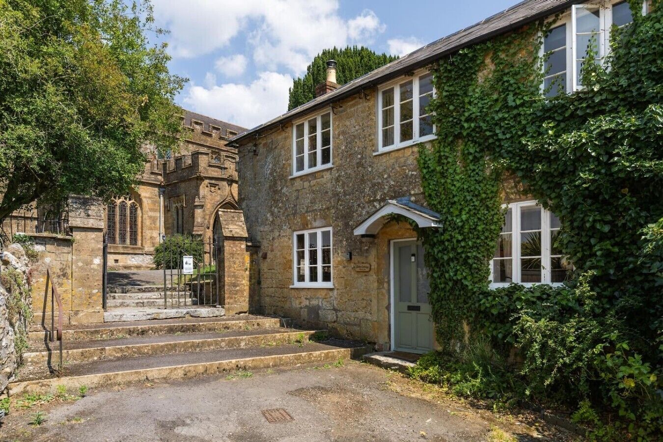A stone building with a traditional design, a gated entrance, and a small set of steps leading to the door.