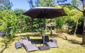 A patio area with a large umbrella, four lounge chairs, and a small table. - The House with the Blue Door – Charm and Authenticity in the Gers (Saint-Orens-Pouy-Petit)