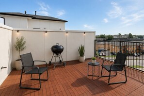 A balcony with a barbecue grill, two chairs, and potted plants. - Luxury Houston Getaway 3BR, 3.5BA, Sleeps 8, Near Downtown (Houston)