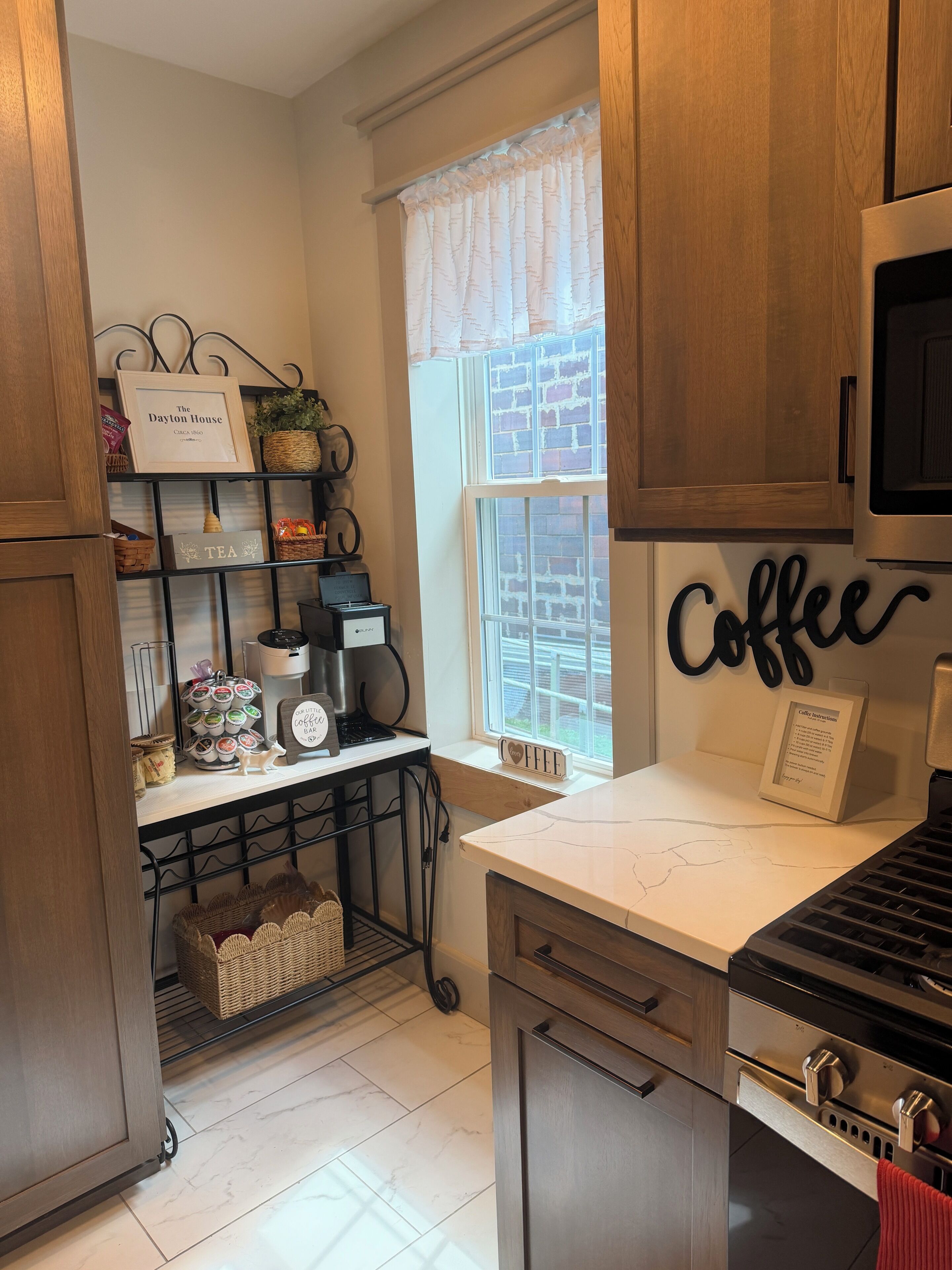 A kitchen with a coffee station, a sign reading 'The Dayton House,' and a window with a view of the outside.
