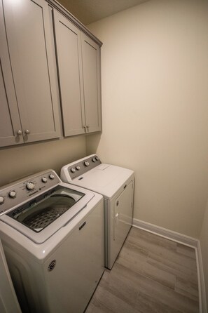 A laundry room with a washing machine, dryer, and cabinets. - Spacious Gulf Breeze Retreat: Near Pensacola & Navarre Beaches & Dining (Gulf Breeze)