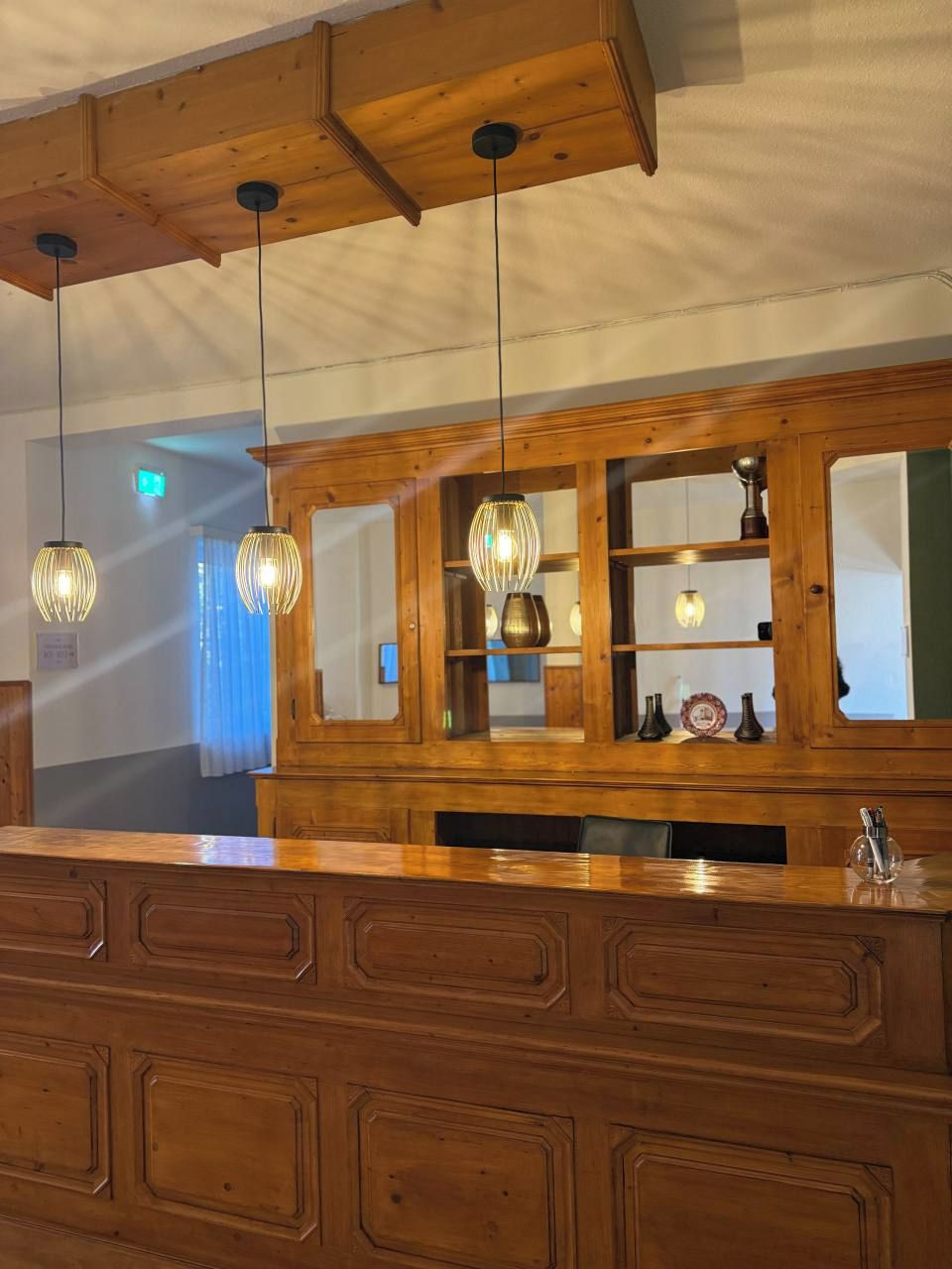 A reception area with wooden paneling, a counter, and hanging pendant lights.