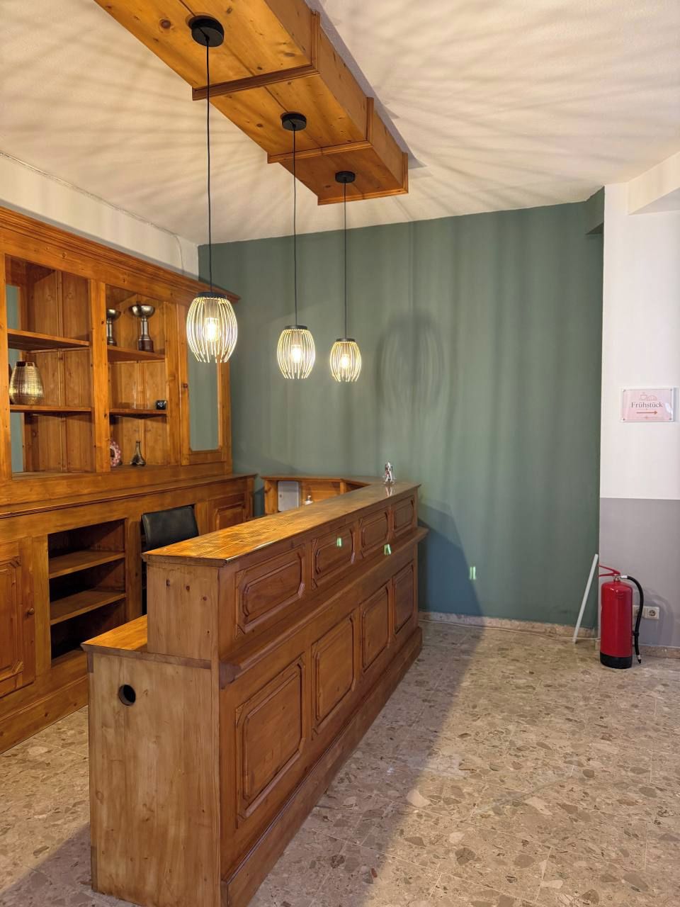 Una habitación con mostrador de bar de madera, luces colgantes y una pared verde.