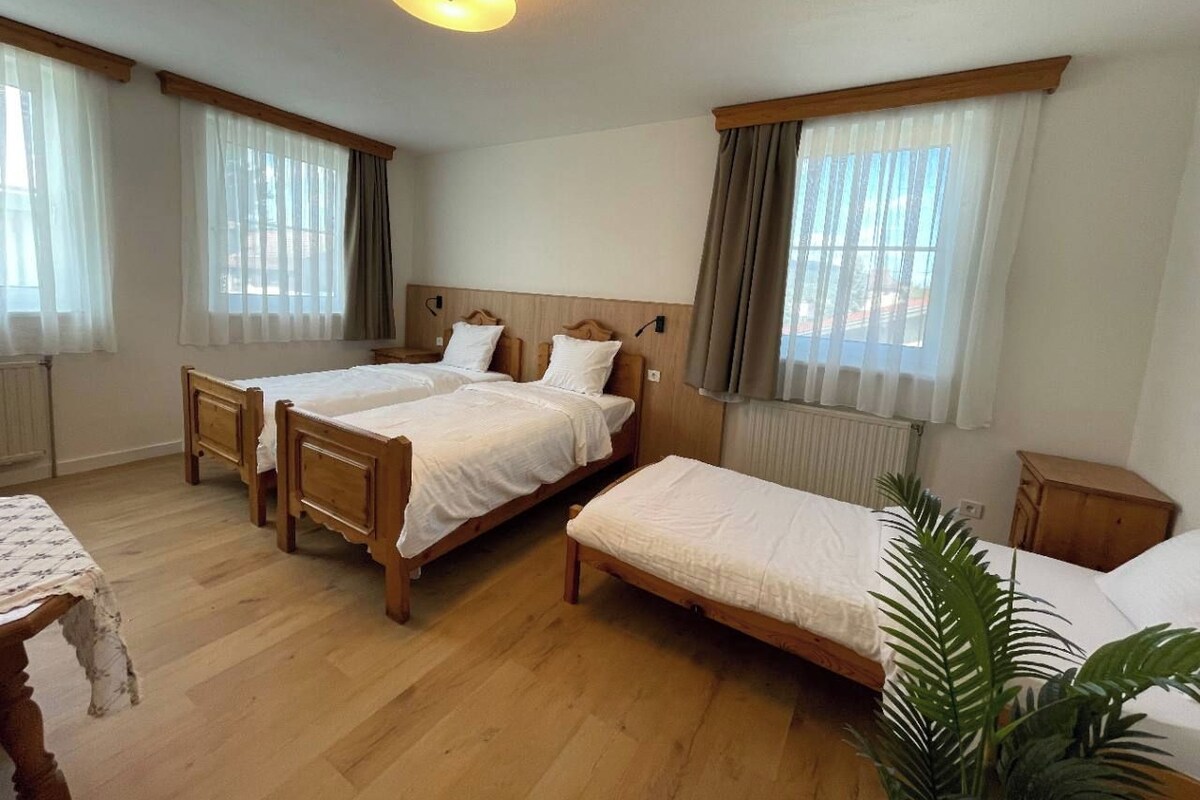 Een kamer met twee houten bedden, een tafeltje en een radiator.