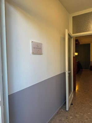 A hallway with a reception sign on the wall, a door leading to another room, and a carpeted floor. - Pension Ursula (Pfaffstätten)