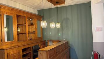 Ein Zimmer mit einer Holztresorecke, einem großen Spiegelkorpus und Pendelleuchten.