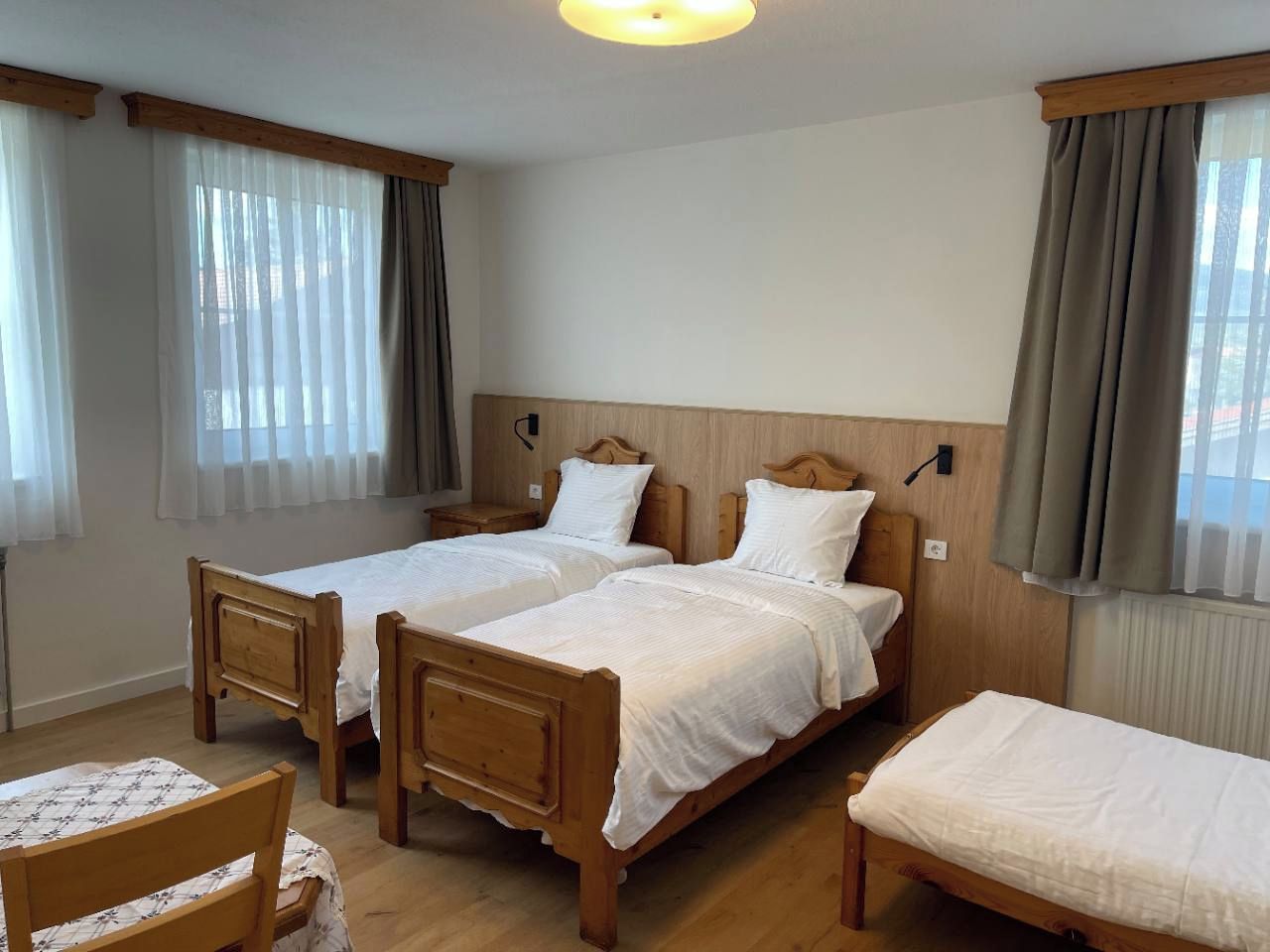 A room with two wooden beds, a wooden chair, and a small table.
